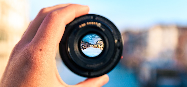 A hand holding a lens with view of buildings upside down